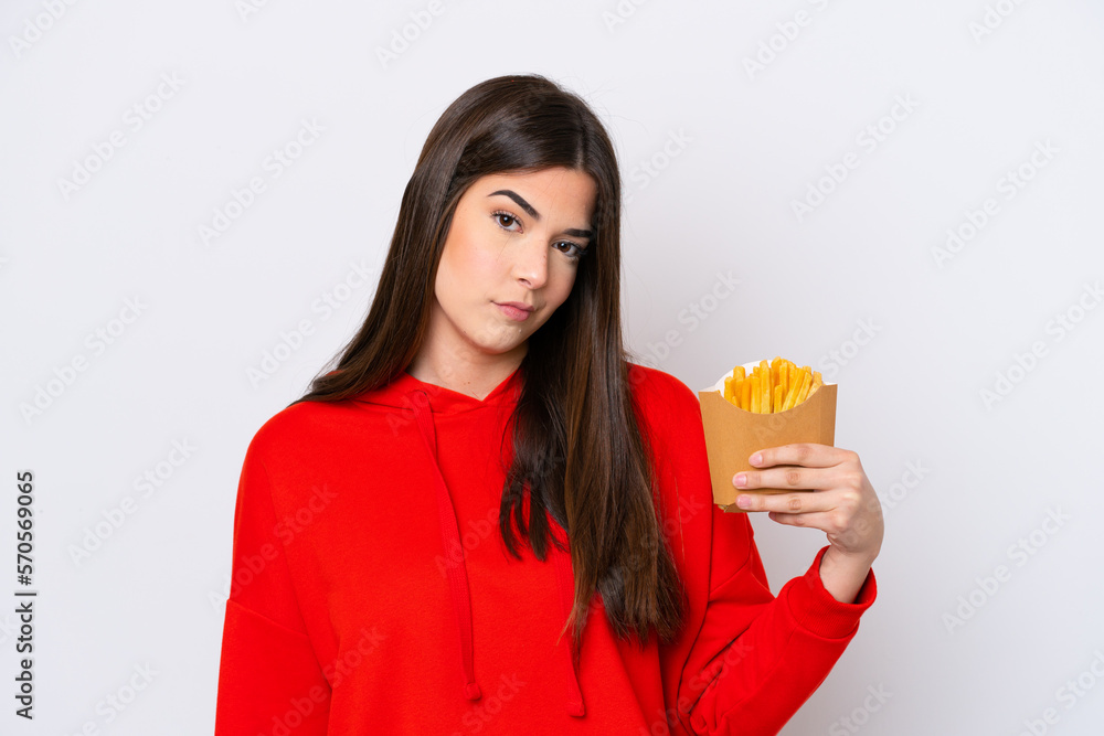 Young Brazilian woman catching french fries isolated on white background with sad expression Young Brazilian woman catching french fries isolated on white background with sad expression