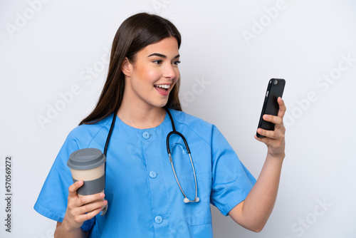 Young Brazilian nurse woman isolated on white background holding coffee to take away and a mobile