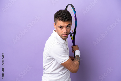 Young Brazilian man isolated on purple background playing tennis © luismolinero