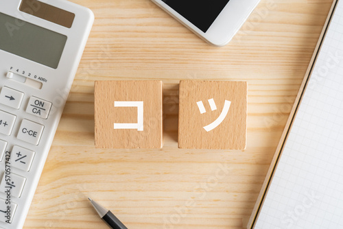 コツと書かれたブロック、電卓、スマホ、ノート