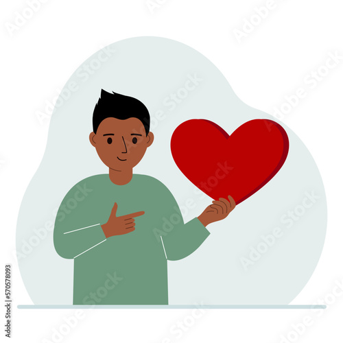 A boy holds a big red heart in his hand. The concept of volunteering, romantic relationship or love.