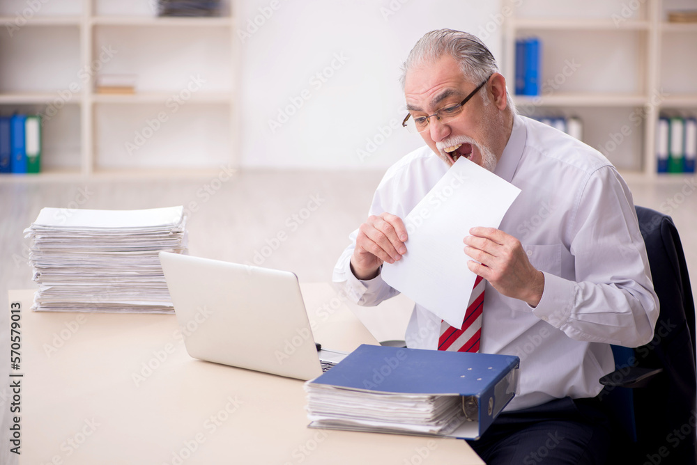 Obraz premium Old male employee and too much work at workplace