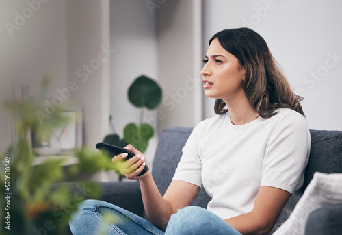 Fotografie Woman confused watching tv, streaming with remote control and relax at home, thinking or vision problem with squint