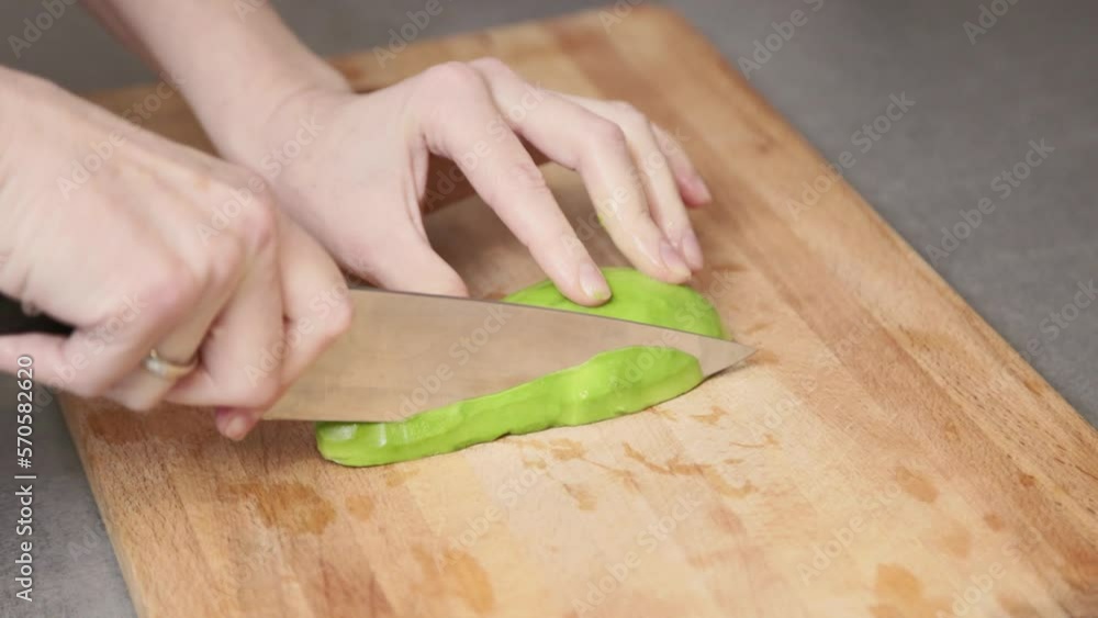 A woman cuts an avocado on a wooden cutting board in the kitchen. Vegan breakfast snack. Video in slow motion. A woman cuts an avocado on a wooden cutting board in the kitchen. Vegan breakfast snack. Video in slow motion.
