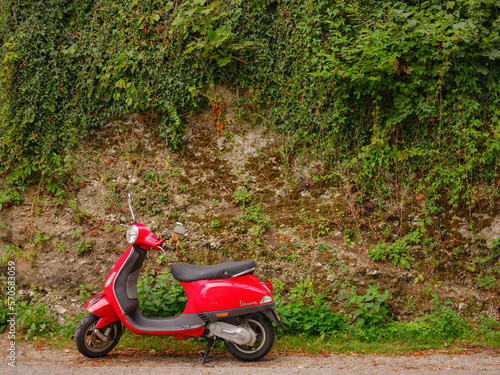 Munich  Germany - August 4  2022   personal transport  a beautiful red Vespa moped stands near a green wall in the city