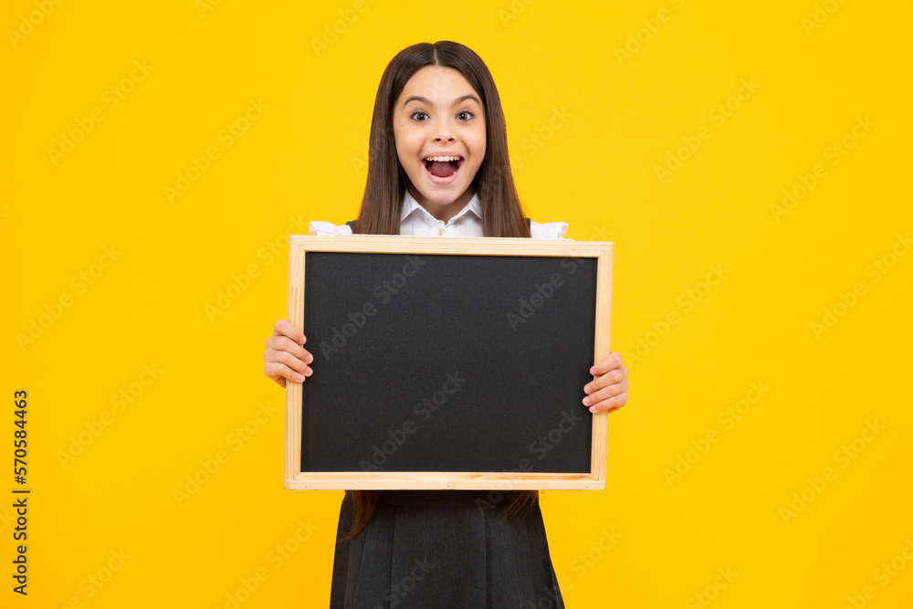 Teenage girl child holding blackboard, isolated on a yellow background. Excited face, cheerful emotions of teenager girl. Teenage girl child holding blackboard, isolated on a yellow background. Excited face, cheerful emotions of teenager girl.