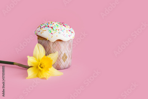 Traditional russian Easter ortodox cake with daffodil flower and colorful eggs on light pink background. Kulic, Kulich, Paska homemade bread with glaze. Spring christian holiday. Festive celebration photo