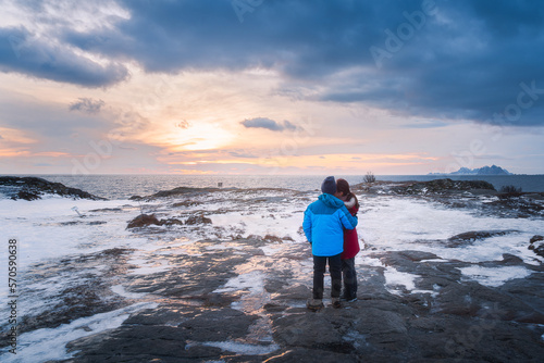 A couple standing on the frozen rock and ice beside the sea