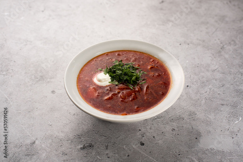Red delicious delicious borscht in a white plate on a gray background