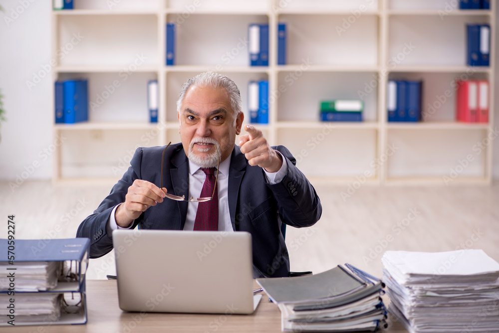 Old male employee sitting at workplace Old male employee sitting at workplace