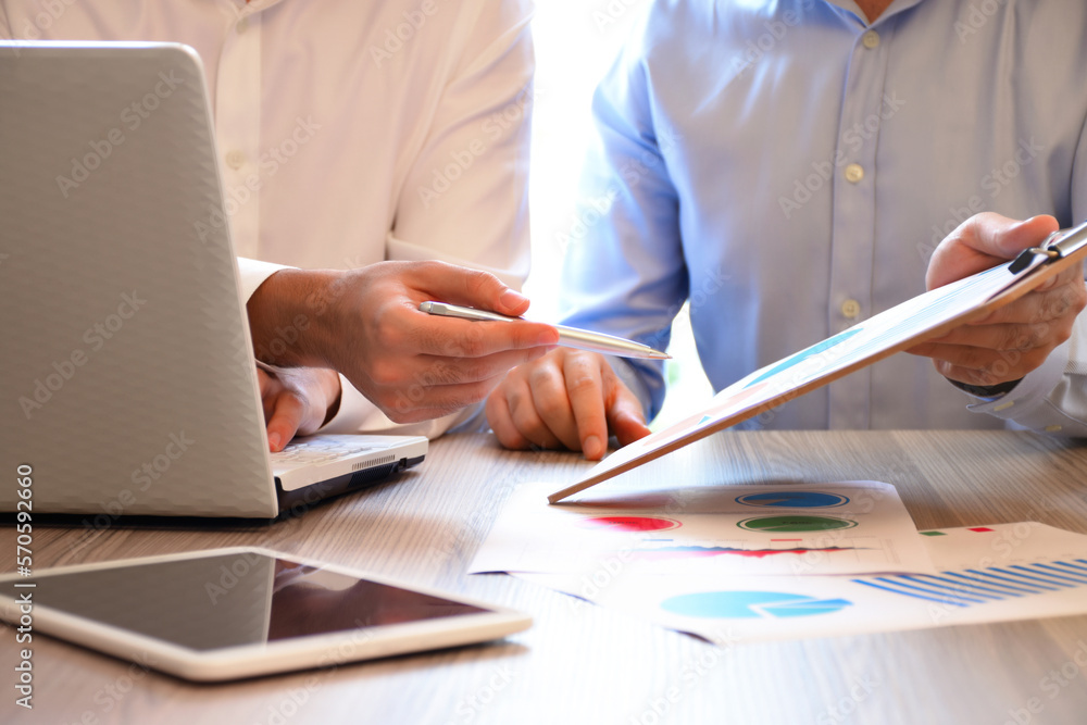 Two business person working on the office desk with business graphs Two business person working on the office desk with business graphs