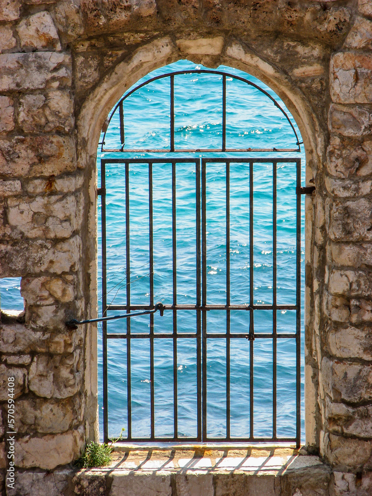 Obraz premium A window in the walls of Dubrovnik's fortified city walls, overlooking the Adriatic Sea.