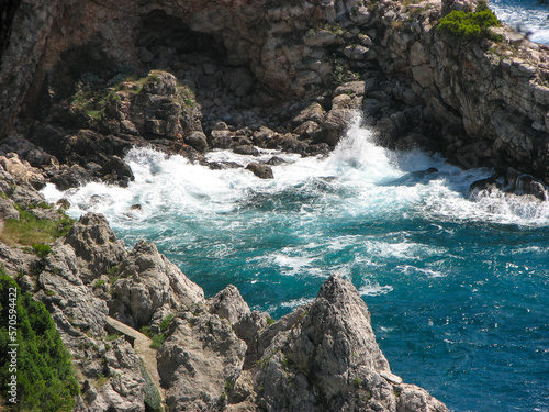 Turquoise water splashing against a rocky shore near Dubrovnik, Croatia.  Image has copy space.