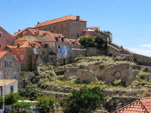 A view from the ground of Dubrovnik, Croatia's famous terra cotta coloured roofs on a hill on a sunny day with a clear blue sky.  Image has copy space.