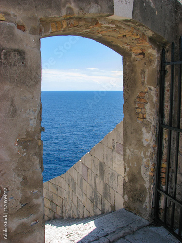 A door in Dubrovnik Croatia's fortified city walls, overlooking the blue water of the Adriatic Sea on a sunny day.  Image has copy space.