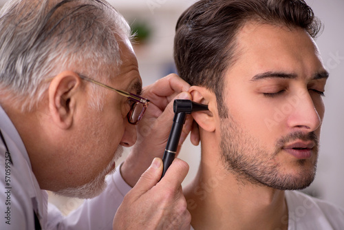 Young male doctor visiting old doctor otolaryngologist