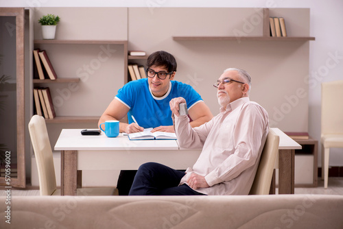 Young male student and his grandfather at home