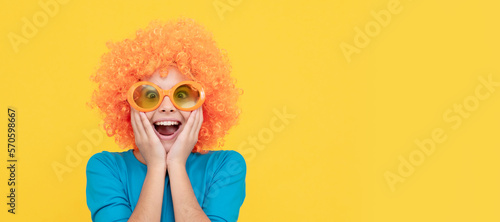 amazed selfish child girl in curly wig and party glasses, amazement. Funny teenager child in wig, party poster. Banner header, copy space.