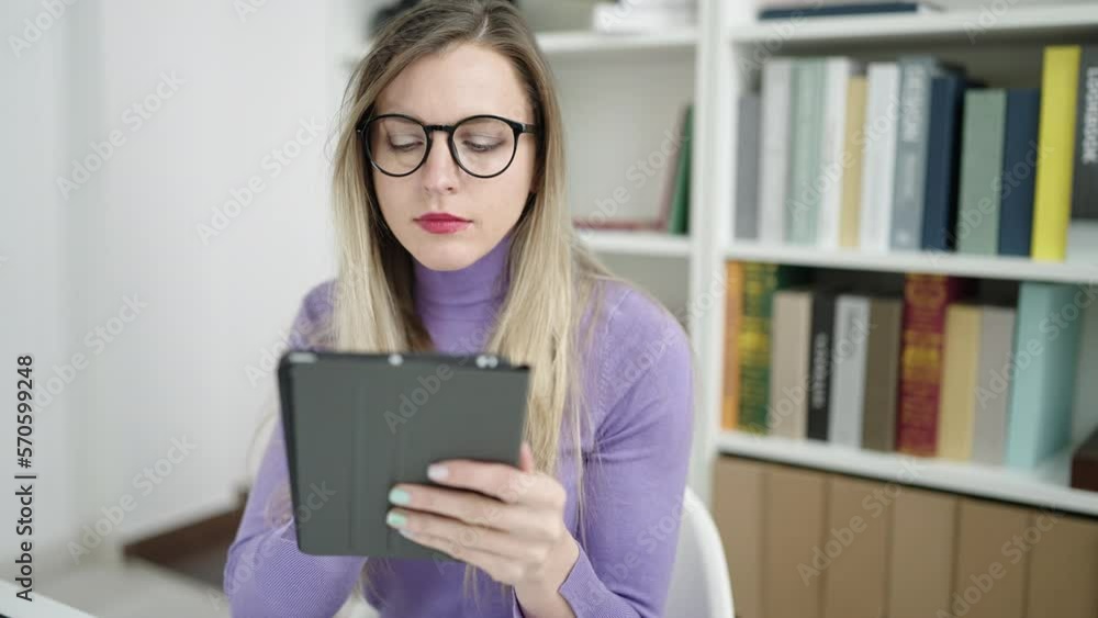 Young blonde woman student using touchpad studying at library university Young blonde woman student using touchpad studying at library university