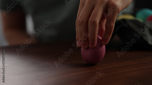 Young man spin easter egg on walnut table