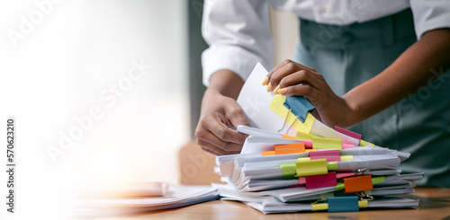 Papier peint Black skin woman hands working in Stacks of paper files for searching and checki