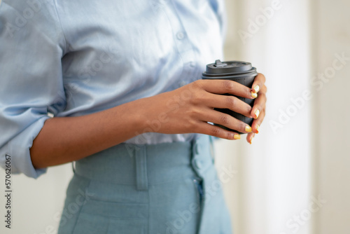 Black woman holding a mug of hot coffee with two hands