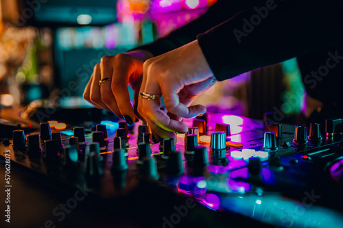 Fotografiet DJ Hands creating and regulating music on dj console mixer in concert nightclub