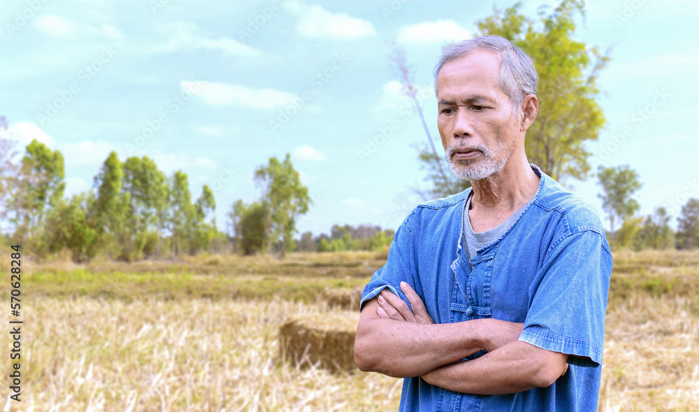 Portrait of an elderly Asian farmer worried about the weather for farming.