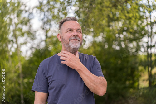 Pensive middle aged man with hand to throat