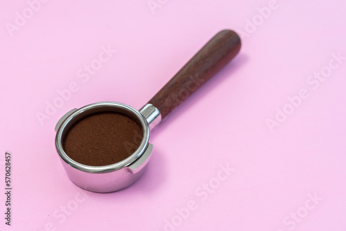 basket of portafilter and roast coffee beans on pink background