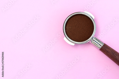basket of portafilter and roast coffee beans on pink background photo