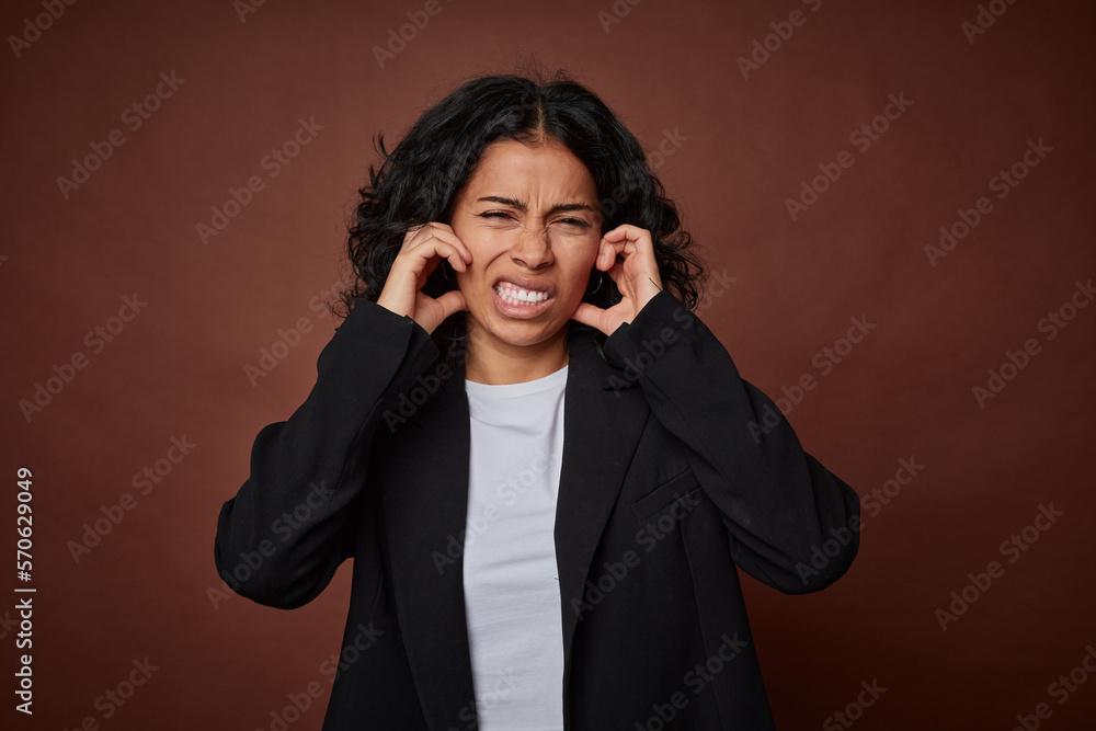 A young business colombian woman covering ears with hands. A young business colombian woman covering ears with hands.