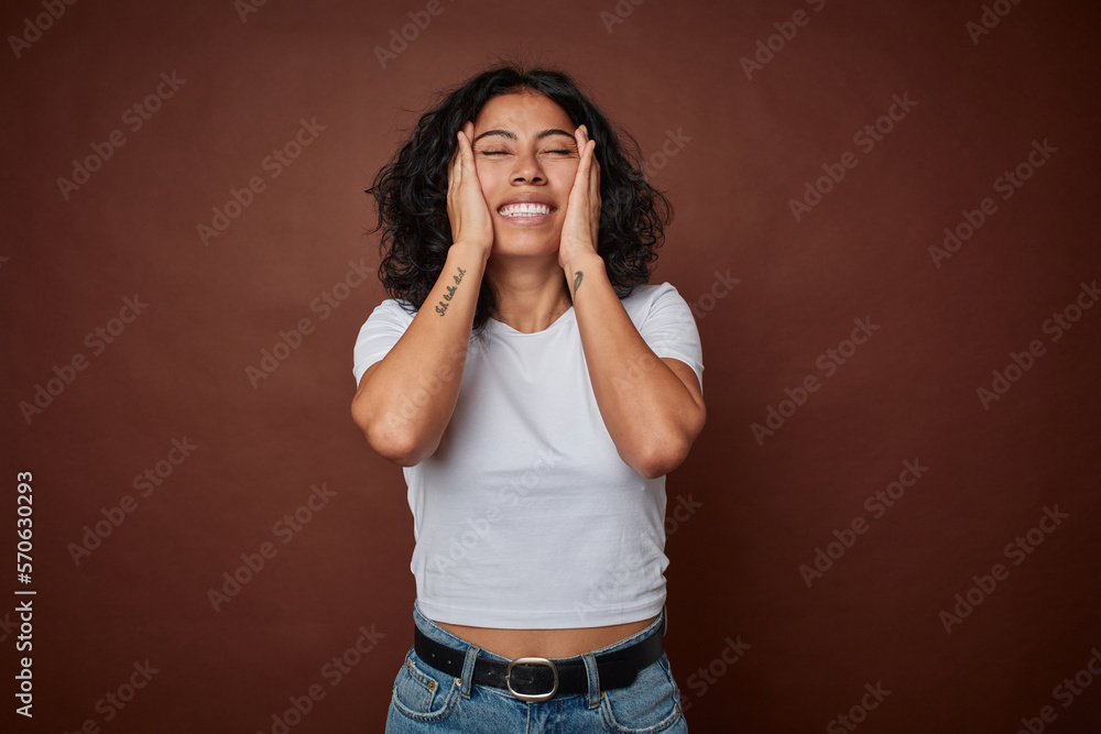 Young colombian curly hair woman isolated on brown background laughs joyfully keeping hands on head. Happiness concept. Young colombian curly hair woman isolated on brown background laughs joyfully keeping hands on head. Happiness concept.