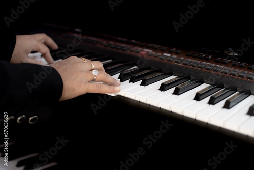 Close up of both Hands of young women playing piano, women is wearing black formal coat playing classical  note  