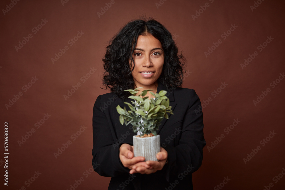 Young businesswoman holds a plant, symbolizing sustainable business practices. Young businesswoman holds a plant, symbolizing sustainable business practices.