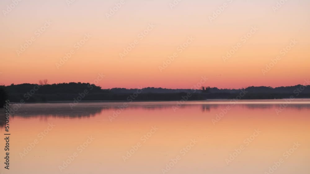 Sunrise over lake and beautiful morning landscape. Morning sun breaks through the thick fog. Early morning on calm river with fog. Fantastic foggy river in the golden sunlight on water surface Sunrise over lake and beautiful morning landscape. Morning sun breaks through the thick fog. Early morning on calm river with fog. Fantastic foggy river in the golden sunlight on water surface