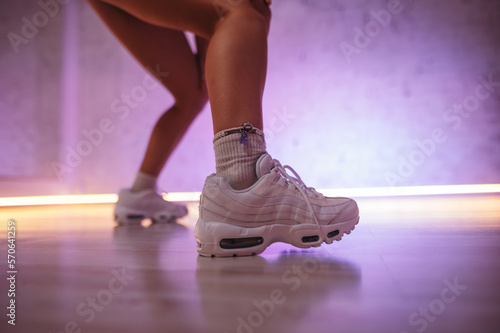 Close-up photo of female dancer's legs in sneakers while dancing. Fashionable sneakers on the legs of a dancer.