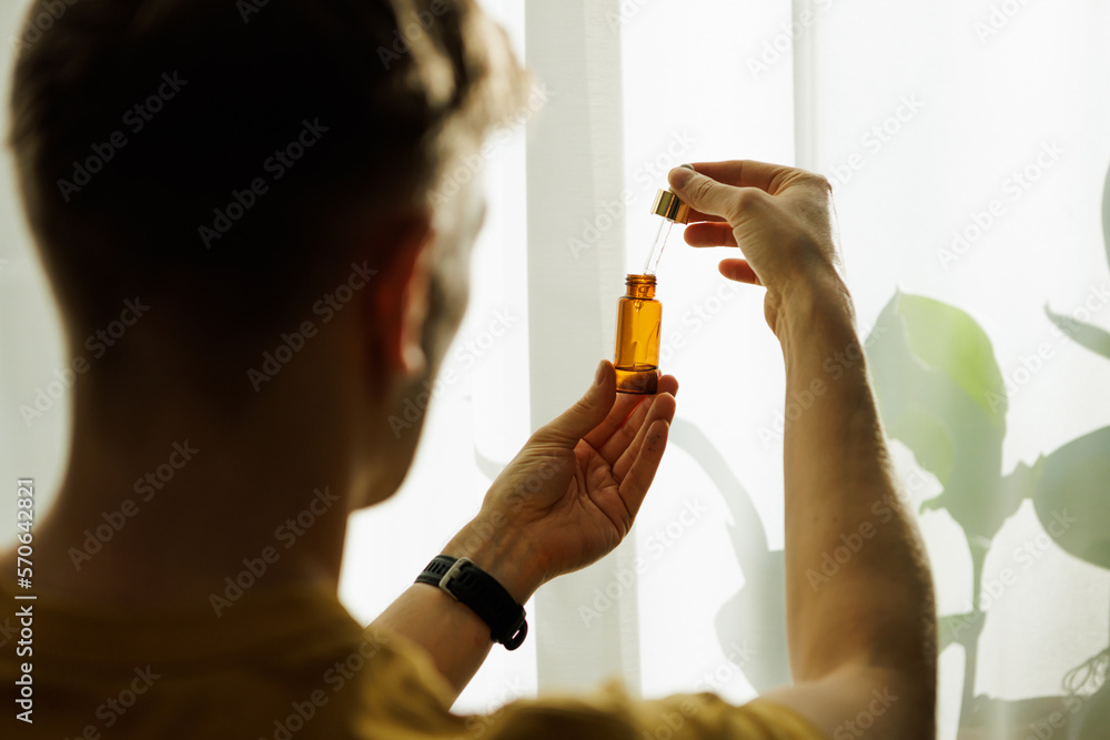 Fototapeta premium Positive Professional Taking Care of Their Mental and Physical Health with CBD Tincture for Stress and Anxiety Relief. Holding a Bottle of Hemp Oil, a Popular Supplement for a Healthy Lifestyle