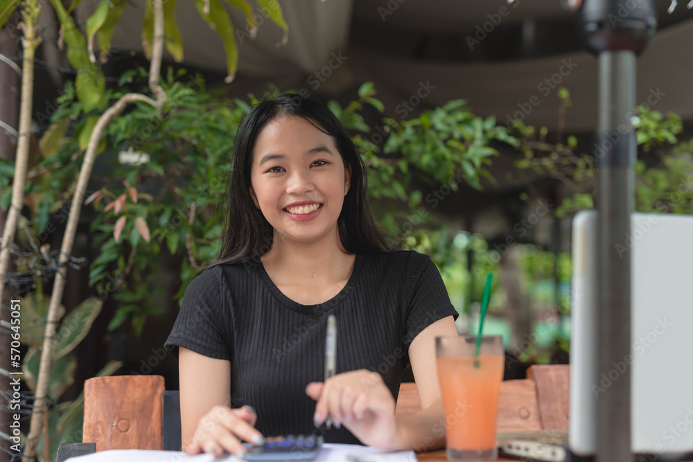 A pretty teenage girl smiles for the camera with a pen in her hand while chilling at a coffee shop. A pretty teenage girl smiles for the camera with a pen in her hand while chilling at a coffee shop.