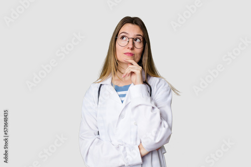 фотографія Compassionate female physician with a stethoscope around her neck, ready to diagnose and care for her patients in her signature white coat looking sideways with doubtful and skeptical expression