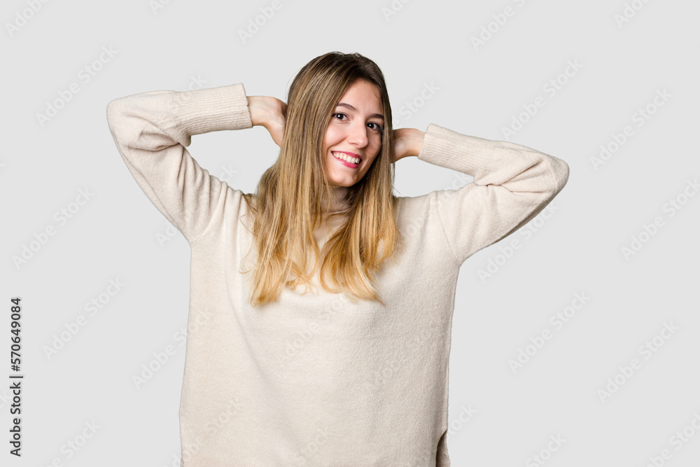 Young blonde posing for a portrait isolated, exuding natural beauty and radiance stretching arms, relaxed position. Young blonde posing for a portrait isolated, exuding natural beauty and radiance stretching arms, relaxed position.