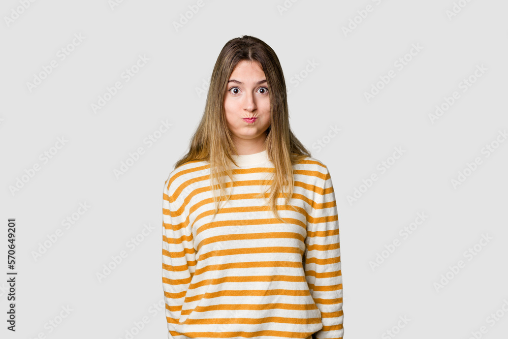 Young blonde posing for a portrait isolated, exuding natural beauty and radiance blows cheeks, has tired expression. Facial expression concept. Young blonde posing for a portrait isolated, exuding natural beauty and radiance blows cheeks, has tired expression. Facial expression concept.