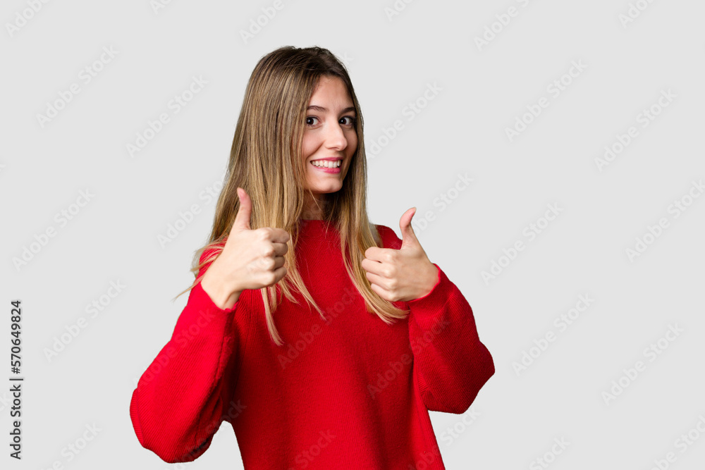 Young blonde posing for a portrait isolated, exuding natural beauty and radiance raising both thumbs up, smiling and confident. Young blonde posing for a portrait isolated, exuding natural beauty and radiance raising both thumbs up, smiling and confident.