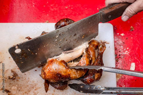 Chopping Lechon Manok, a FIlipino spit-roasted chicken, into pieces for takeout. photo