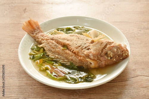 spicy boiled fried red bass fish and  herb in tom yum soup on plate