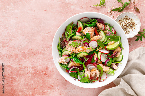 Salmon salad bowl with fresh radish, cucumber, red onion and green mixed leafy vegetables. Healthy diet food, lunch menu. Top view