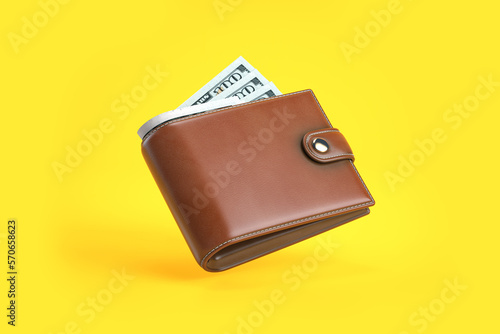 urse or wallet with money dollar bills on yellow background. photo