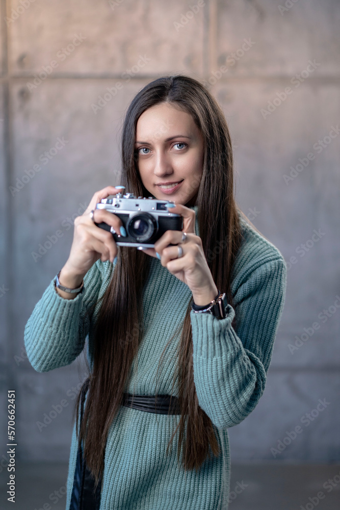 beautiful girl with an old camera in her hands in a green dress. looking at the camera smiling