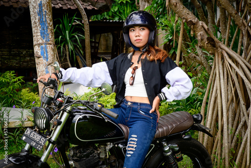 Beautiful brunette woman sits on a black motorcycle with a helmet