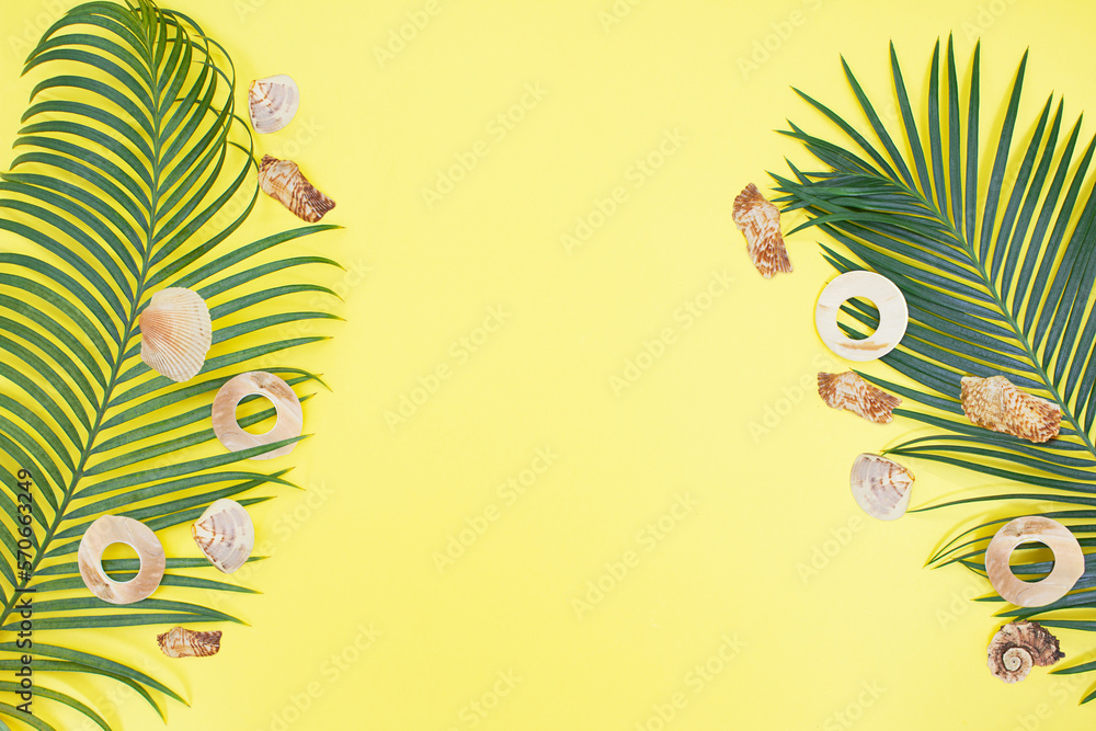 Palm branch with seashells on sides on summer yellow background. Vacation, travel concept, flat lay, top view, minimal exotic concept. Copy space Palm branch with seashells on sides on summer yellow background. Vacation, travel concept, flat lay, top view, minimal exotic concept. Copy space